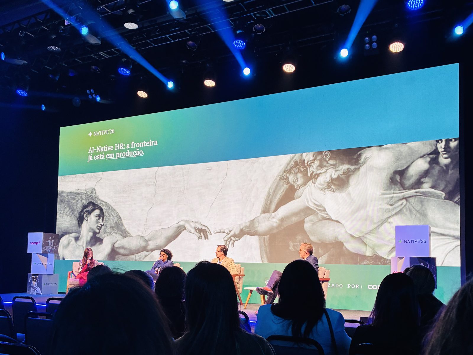 O painel de cases do NATIVE'26 no palco, com o telão "AI-Native HR: a fronteira já está em produção"